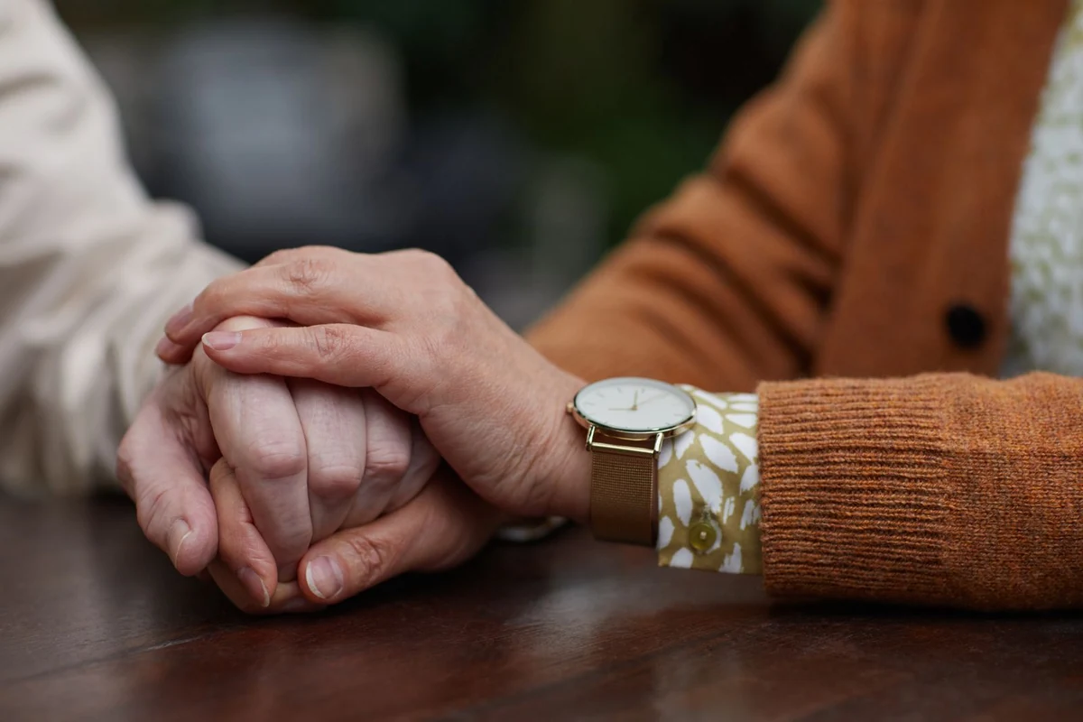 Mãos de duas pessoas sobre uma mesa, em gesto de apoio.
